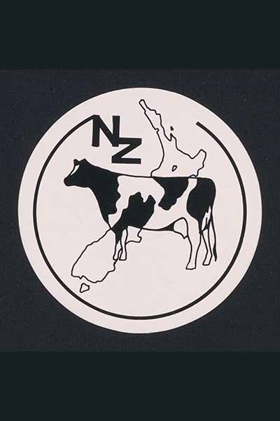 An image of a round black and white sticker. The image on the sticker shows a map of New Zealand with a black and white cow superimposed over the top.
