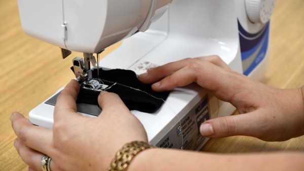 A small piece of black fabric being fed through a sewing machine.