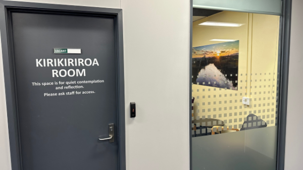 Entrance to the Kirikiriroa Room. The door says This space is for quiet contemplation and reflection. Please ask staff for access. There is a window into the room, with an open blind and partially obscured by privacy film.