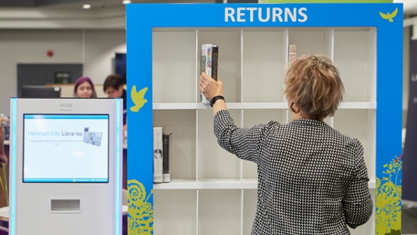 Person placing books on returns shelf