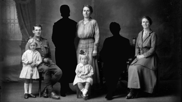 Black and white family portrait from 19th century. Some people are visible only as silhouettes.