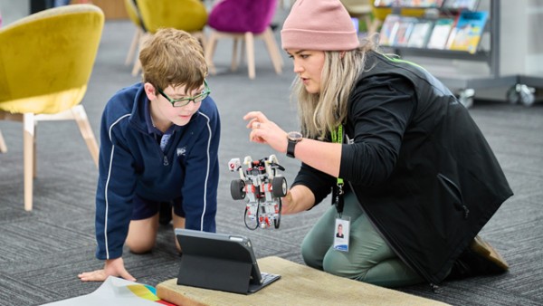 Librarian and young child playing with a robot